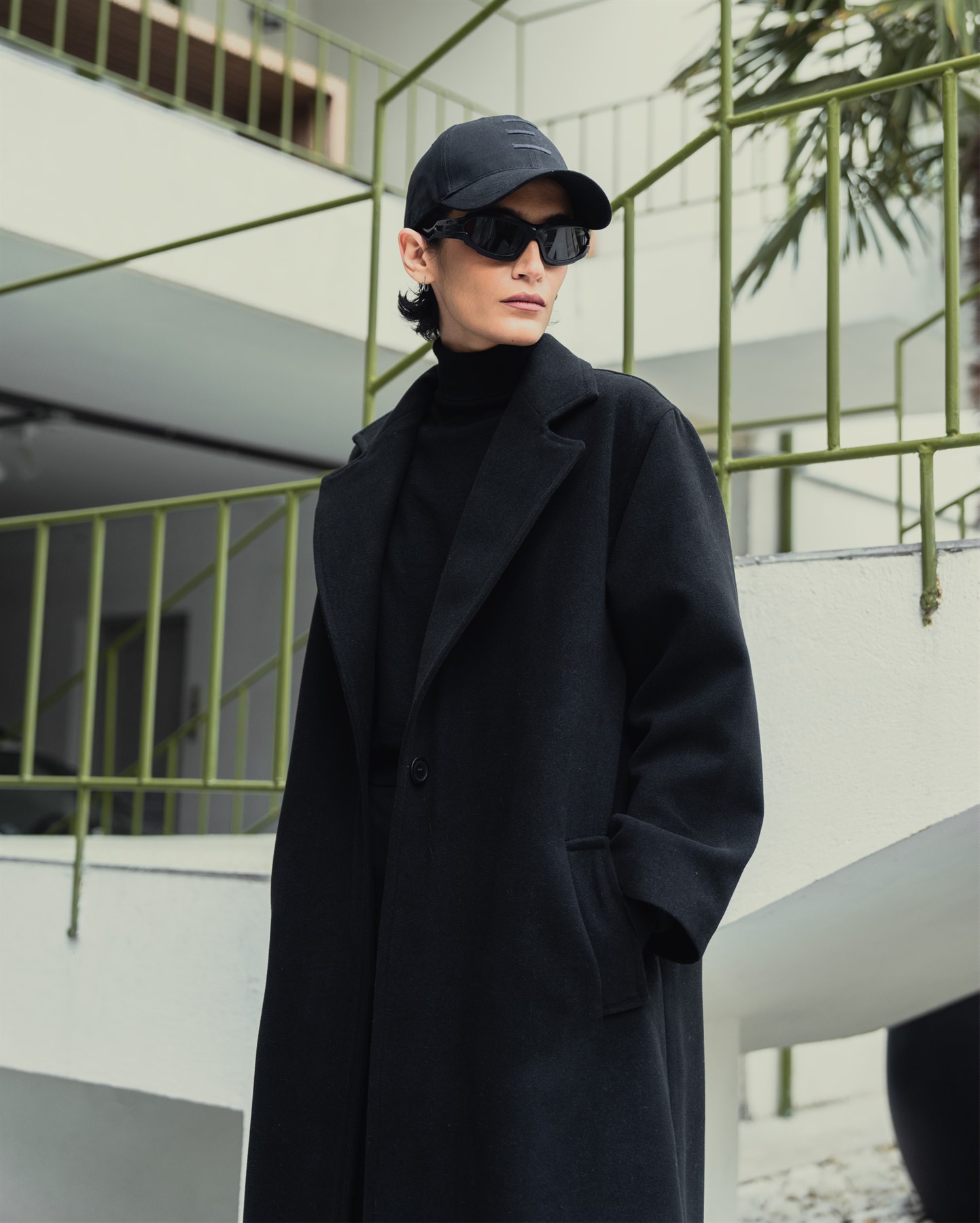 Model wearing a black tailored coat and cap