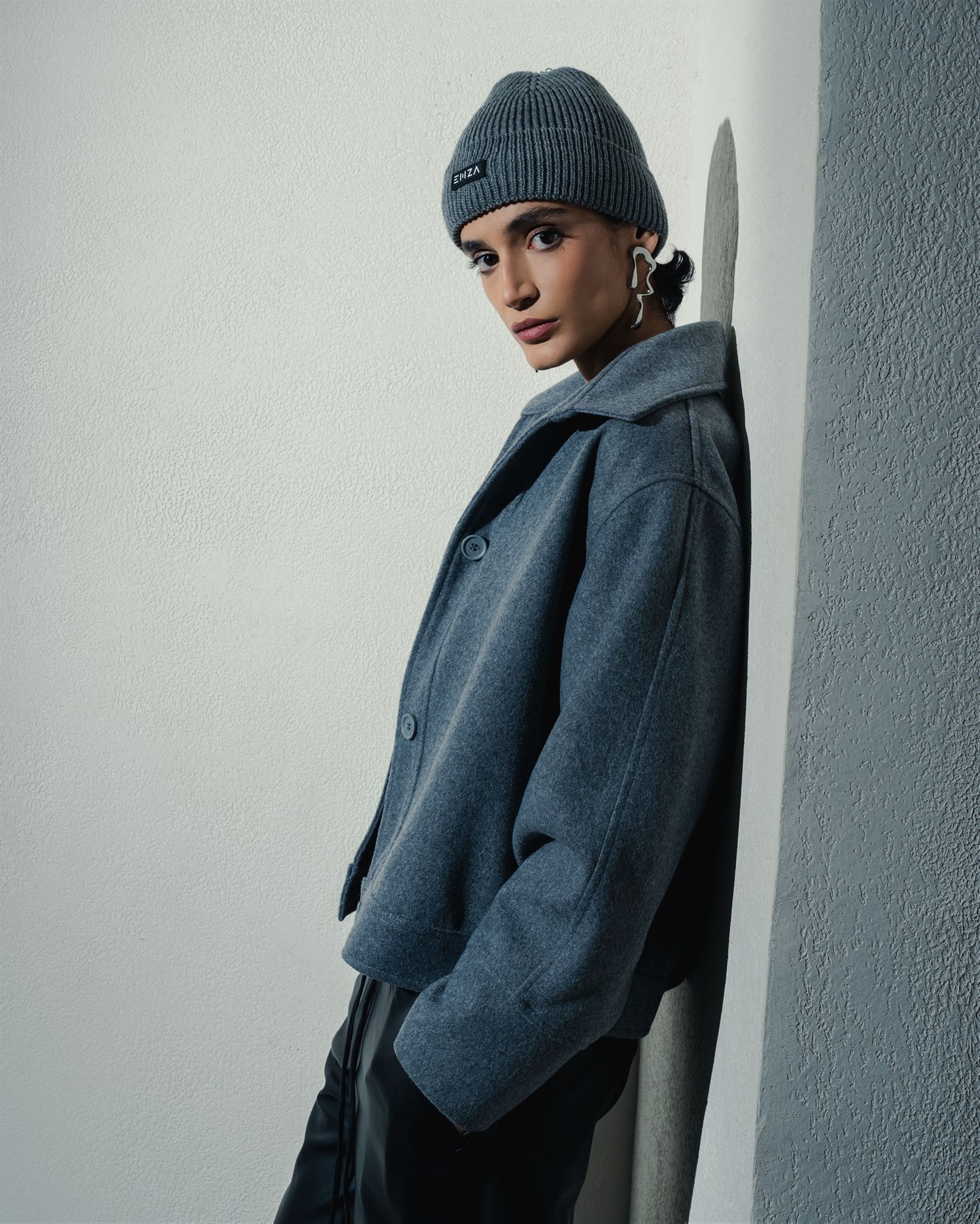 Model wearing a grey structured coat and knit beanie